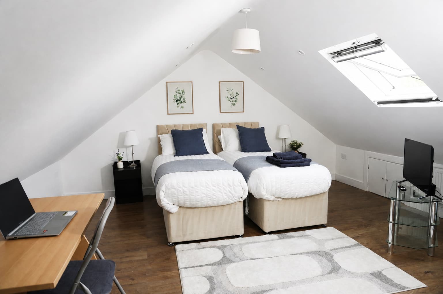 Loft bedroom with two single beds, desk and television