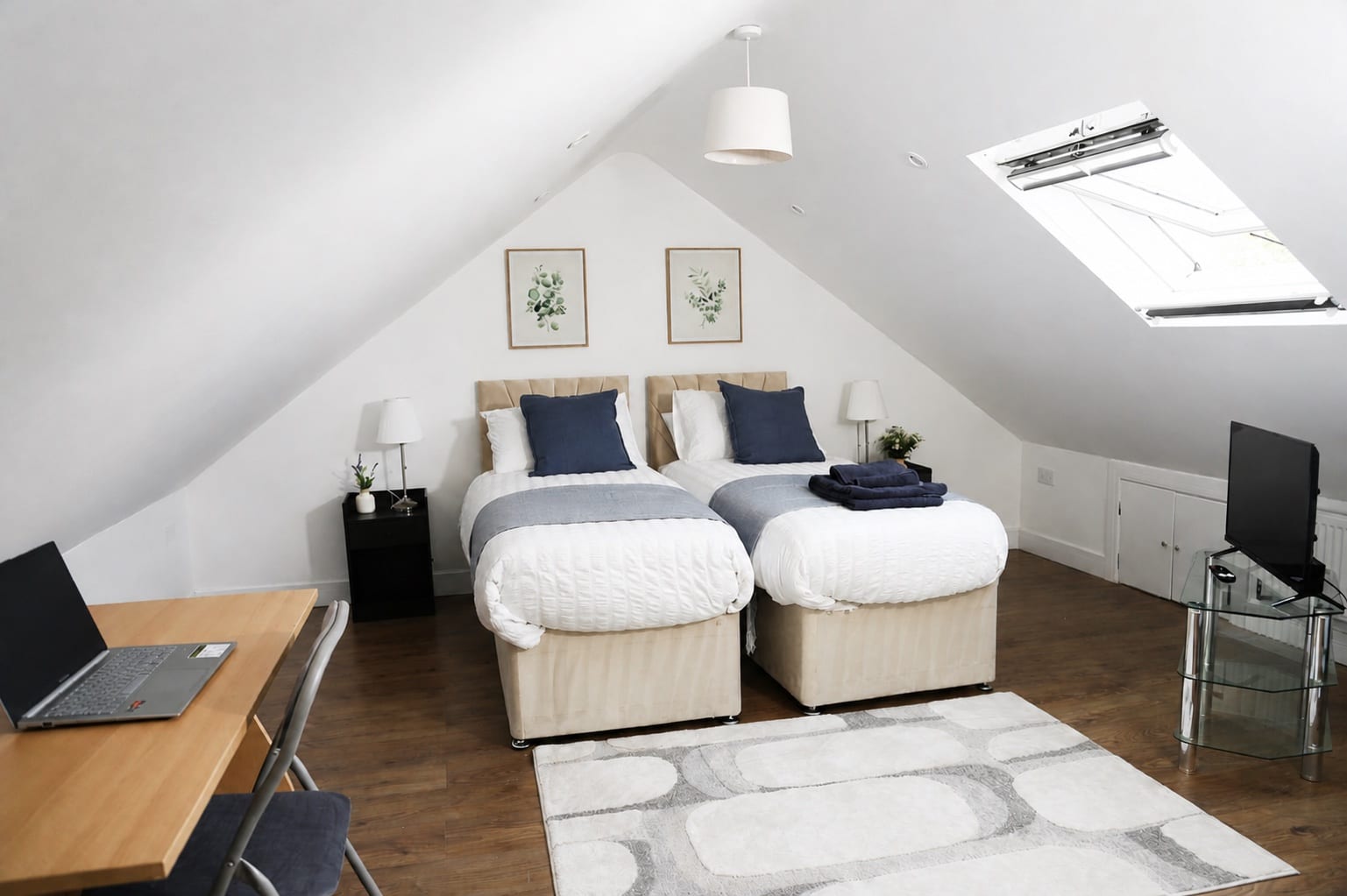 Illustrative twin bedroom with a workspace and television